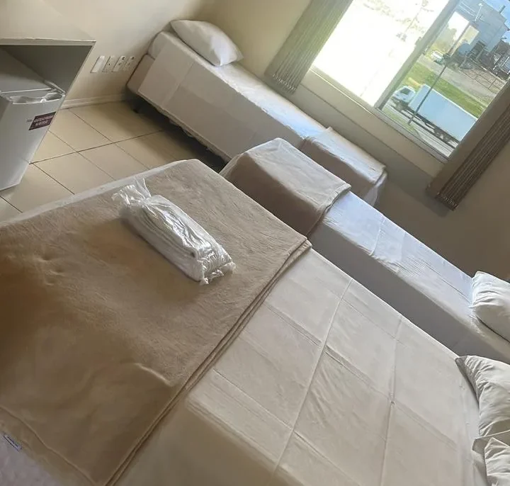 Dois sofás brancos em uma sala com piso de cerâmica, janela ampla com vista para exterior e climatizador na parede
